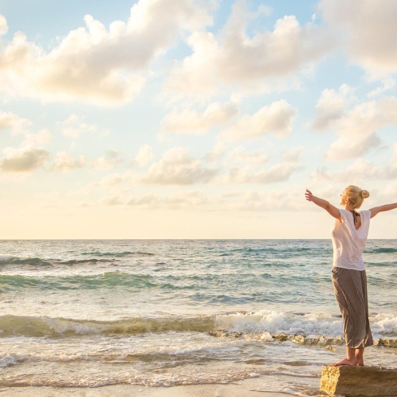 Relaxed woman enjoying sun, freedom and life an beautiful beach in sunset.