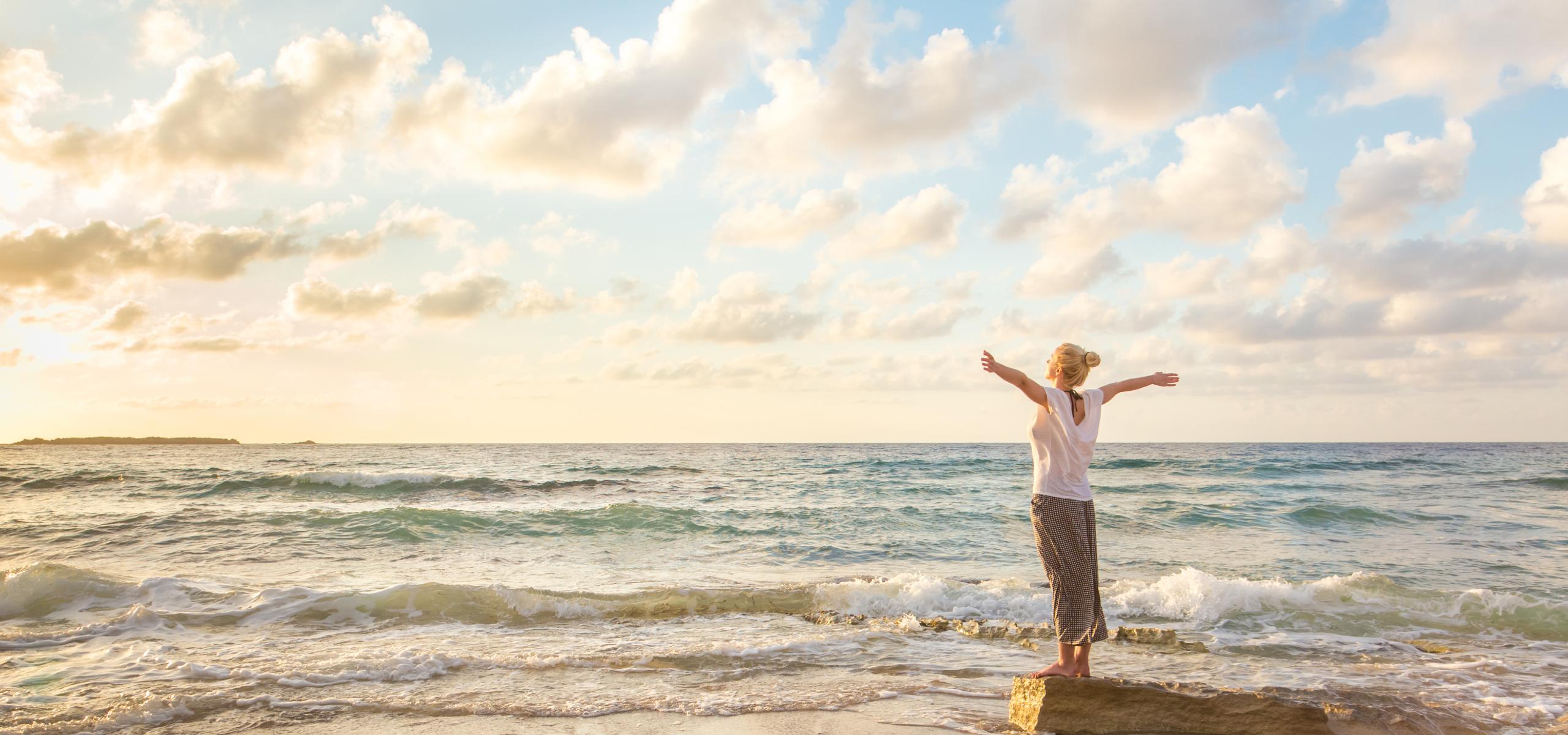 Relaxed woman enjoying sun, freedom and life an beautiful beach in sunset.