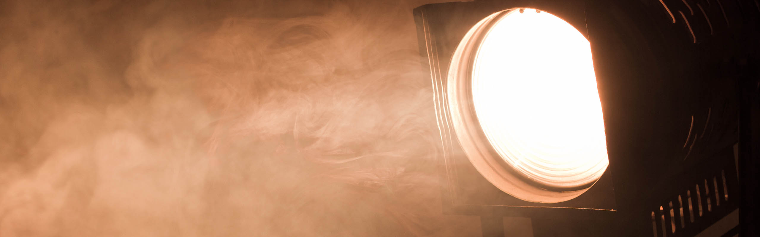 A theatre light shining through some moke.